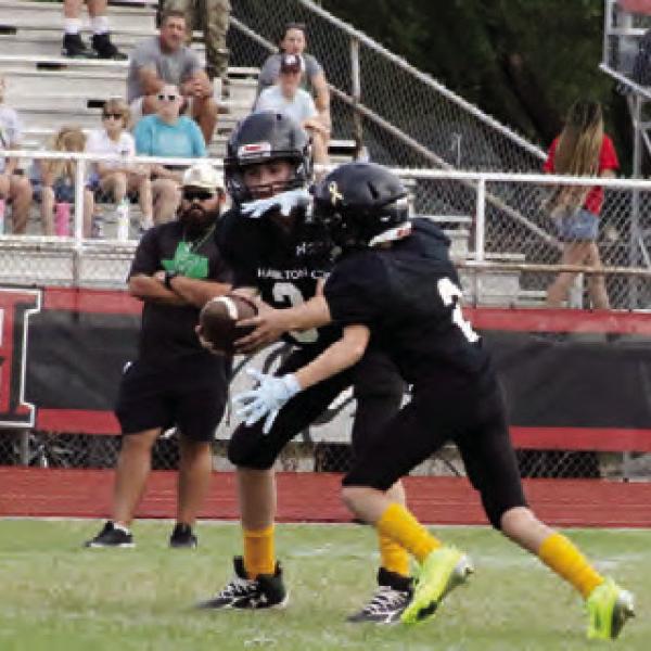 HANDING OFF THE RUN: Kase Leweling handing off the snapped ball to Junior High runner Jace Jones. The 7th grade team scored 44 points off their rushing game and defense against Eastland. Photos by Jaxon Hansard