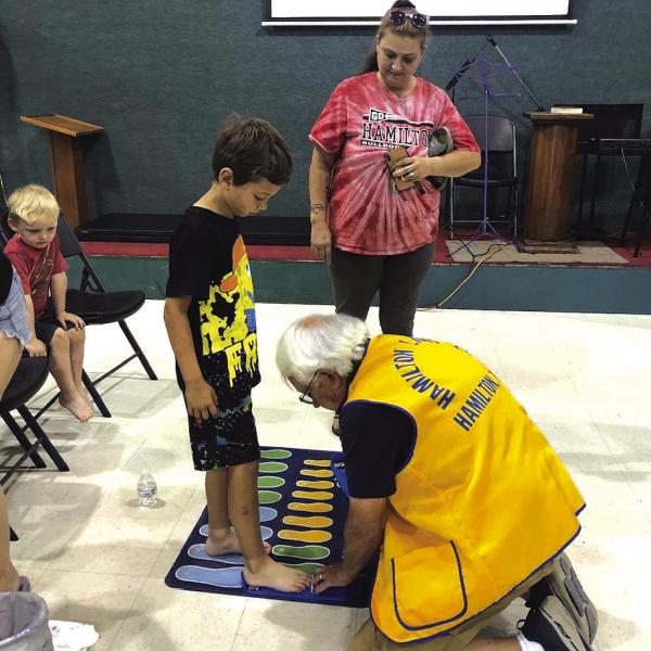 A member of the Hamilton Lions Club’s helps a child find his shoe size during last year’s First Blessing shoe event. Courtesy photo