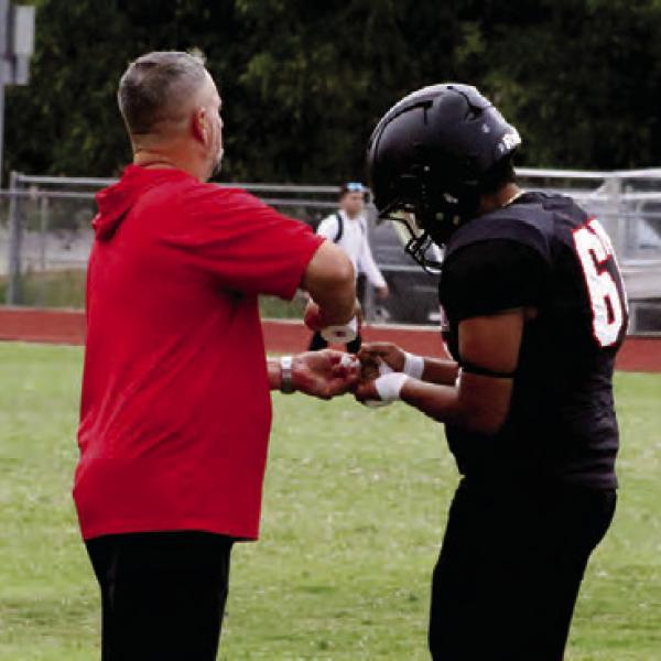 TAPE EM UP: Defensive coordinator Zach Wood taping up Antwan Buitron’s fingers during a timeout. Photos by Jaxon Hansard