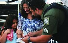  At last Tuesday’s National Night Out, HCSO Sgt. Pollard instructs a young attendee and her mother on how to kick off their sticker scavenger hunt.