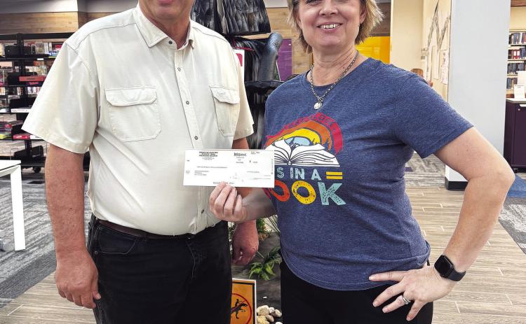 Hamilton County Judge James Yates presented Hamilton Public Library Director Kym Jeschke with a donation to support literacy programs at the local library.