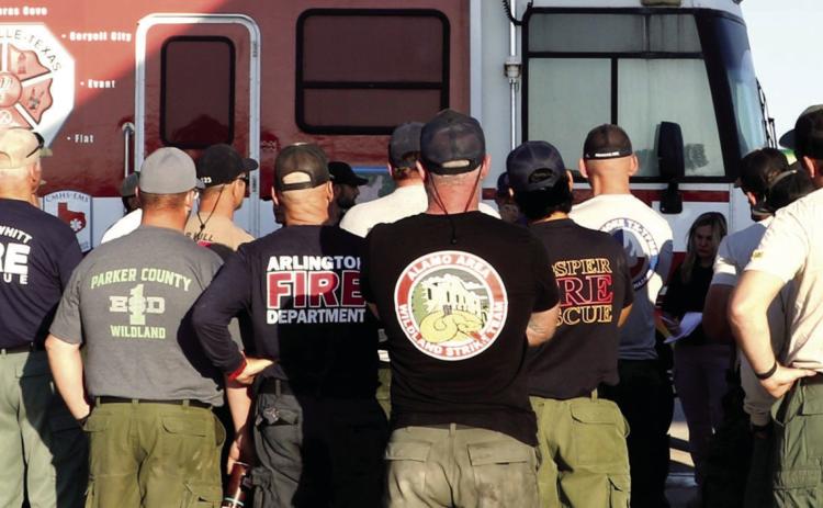 Firefighters and paramedics representing a multitude of cities and counties throughout the state, listen to a daily briefing before heading out to work. Photo by Kate Edwards